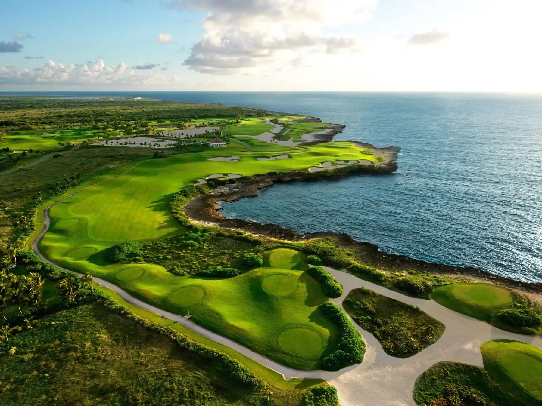 Golden-hour aerial of a clifftop golf course by the sea